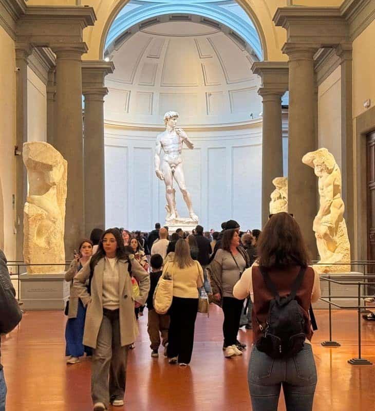 Crowd of visitors gathered around Michelangelo’s statue of David inside the Galleria dell'Accademia in Florence.